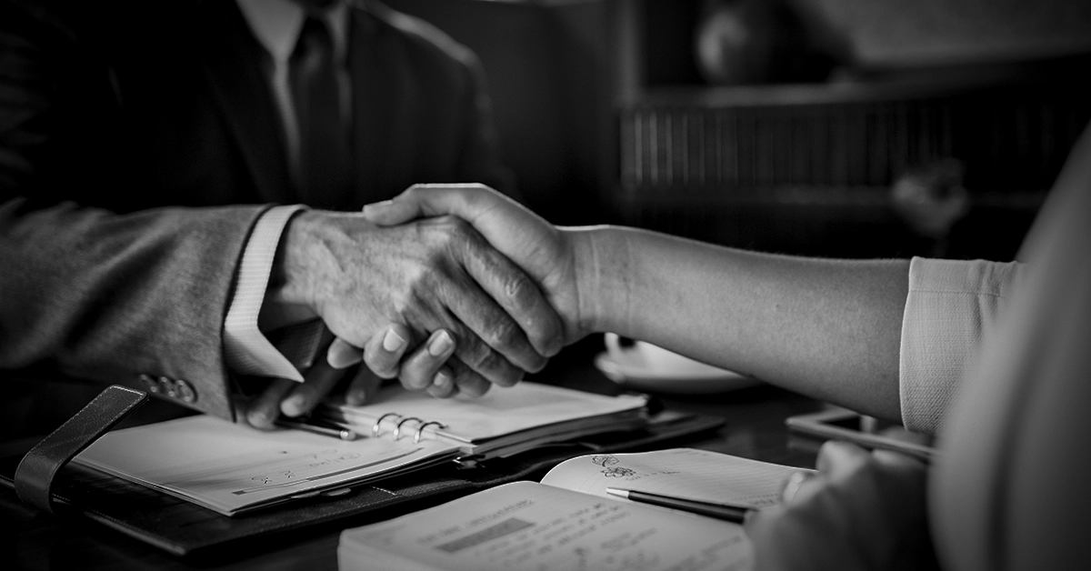 Duas pessoas apertando as mãos sobre documentos legais e anotações – Segurança Jurídica no Candomblé: Até Onde Vai o Acolhimento?